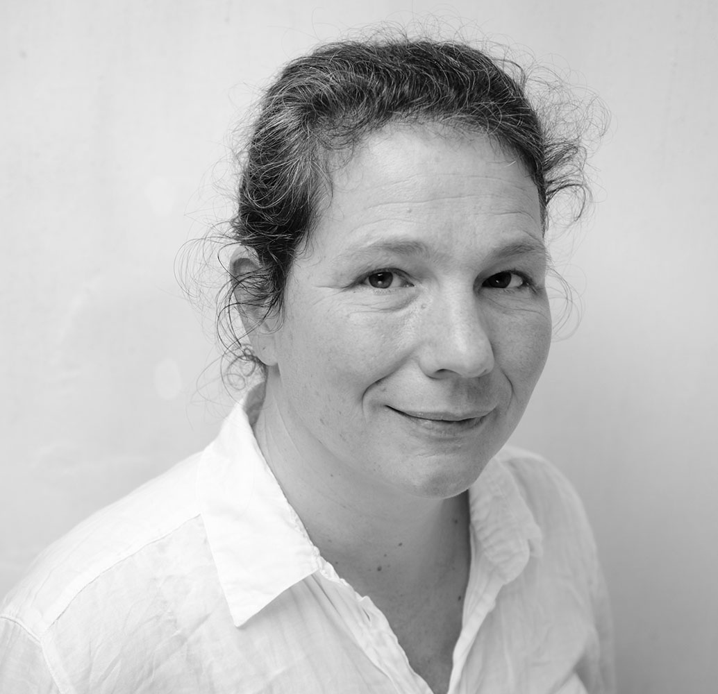 Black and white photograph of the head and shoulders of a woman looking at the camera and smiling.