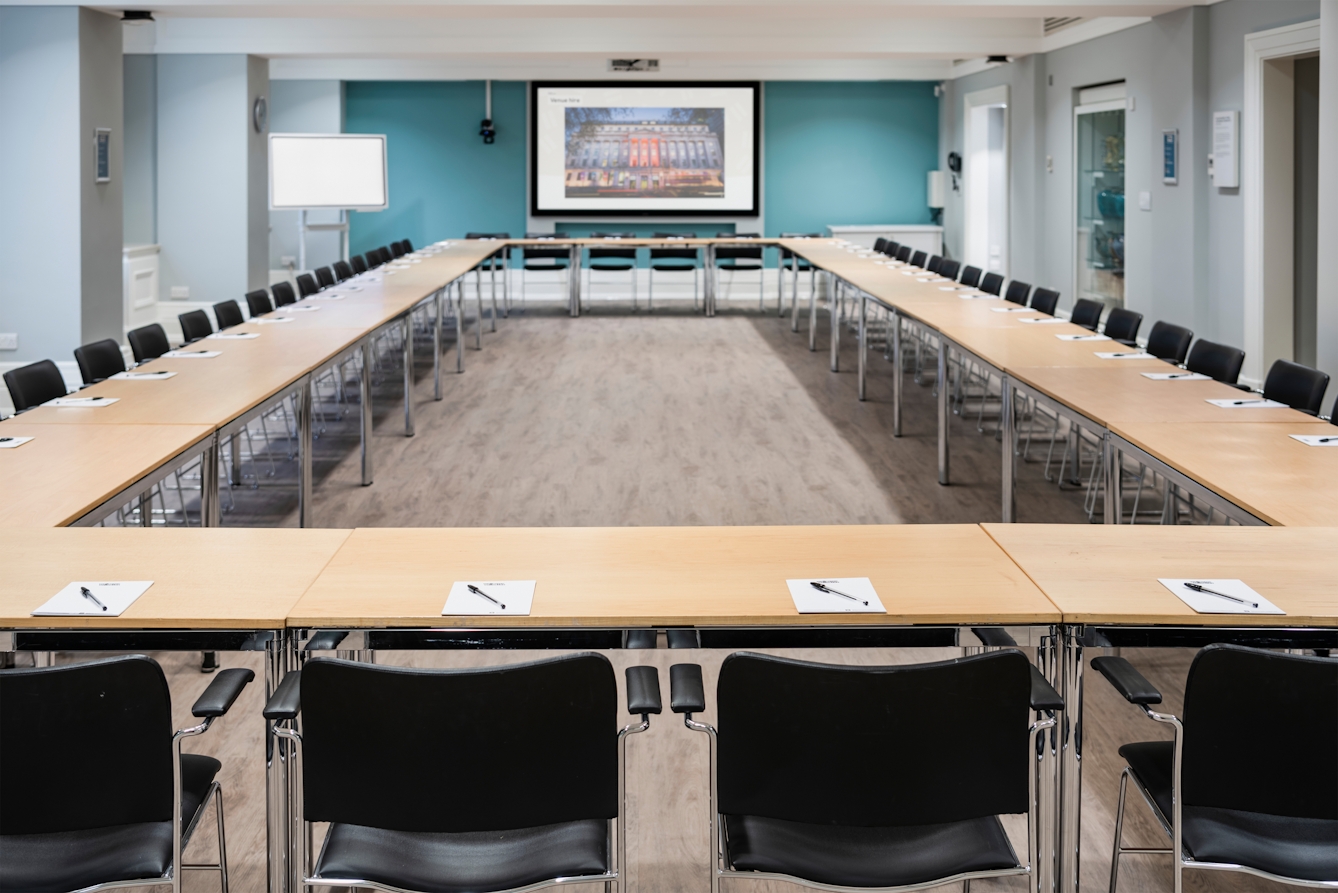 Photograph of the Franks and Steel room at the Wellcome Collection. 

Photograph shows a boardroom set-up., with desks laid together in a rectangle shape with chairs around the outside. 