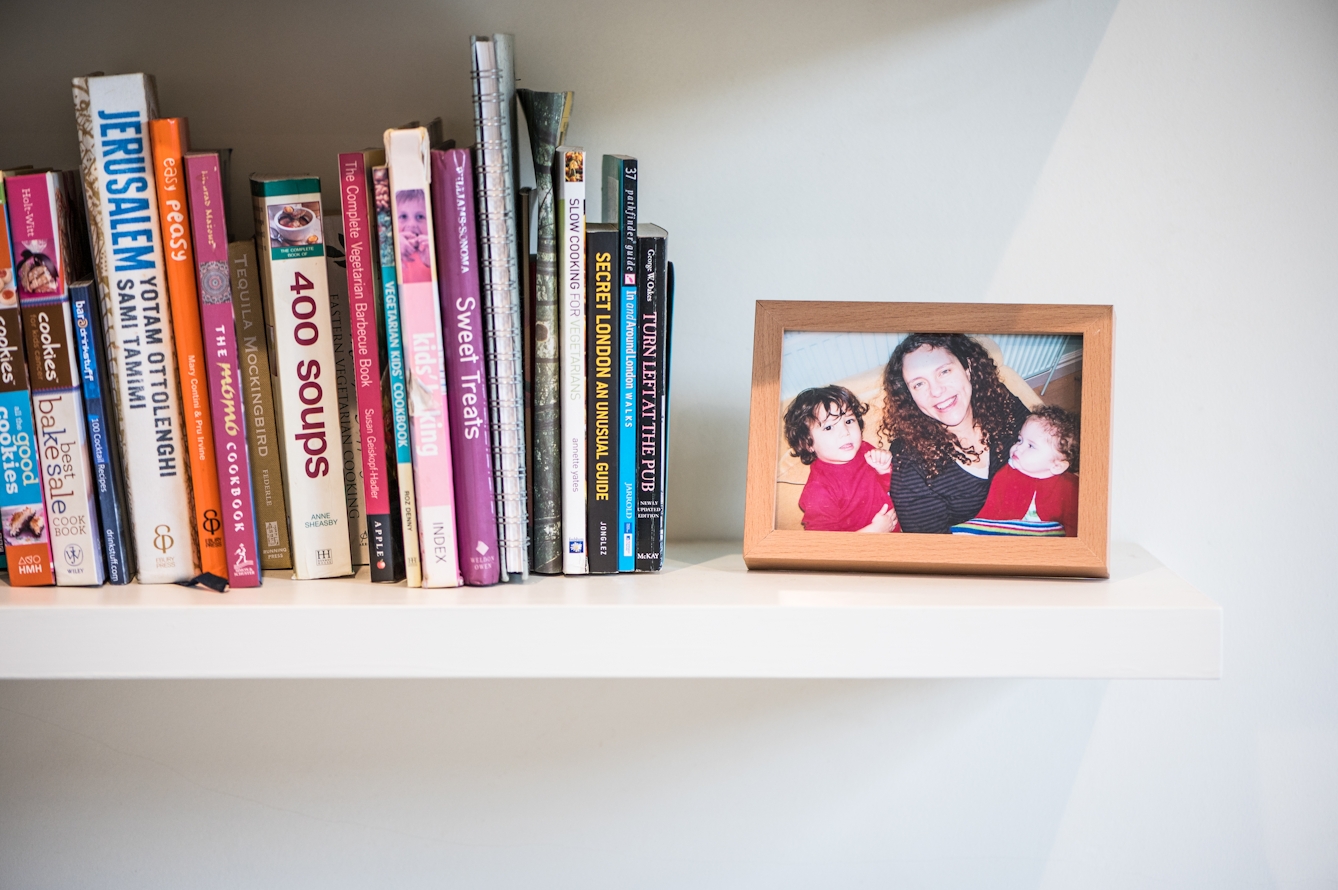 Photograph showing a shelf with a family photo in a frame of a mother and two small children. To the left of the photo is a collection of books.