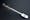 Colour photograph of a surgical implement. It has a silver-coloured device with a long rounded handle and a rounded-shovel-shaped end. There is a cable attached to a "u" shaped device on this end part and running up to a plunger on the handle at the other end.