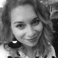 Black and white photograph of the face of a young white woman with fair hair looking straight at the viewer and smiling.