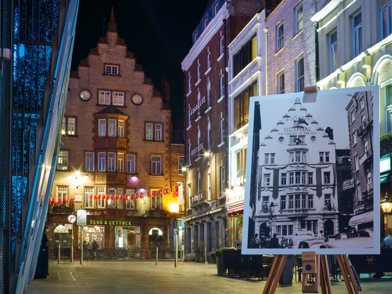 Photograph of the former Hospital for Diseases of the Skin with an historical image of the hospital displayed in front of it on a wooden artist's easel.