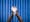 Photograph of a pair of hands cupped together with a large amount of foam sanitiser held in the palms and overflowing down the wrists. Photographed against a background of blue antibacterial clinical curtains.