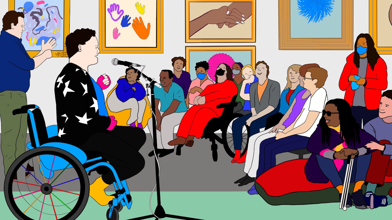 A colourful digital drawing of Jess Thom, a white woman with short curly hair in her blue wheelchair wearing pink fingerless gloves and a black jumper with stars on. She is speaking into a standing microphone to an audience in Wellcome Collection’s Reading Room. Next to her is a BSL interpreter who is communicating in sign language to the audience. People in the audience are smiling and listening to the talk, some are wearing masks. Some people are standing, others are seated on chairs and large cushions. Behind them on the gallery wall are colourful framed illustrations of colourful waving hands, and a pink spherical object.