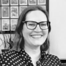 Black and white head and shoulders portrait of Katherine Rawling who has shoulder-length hair and is wearing glasses. 