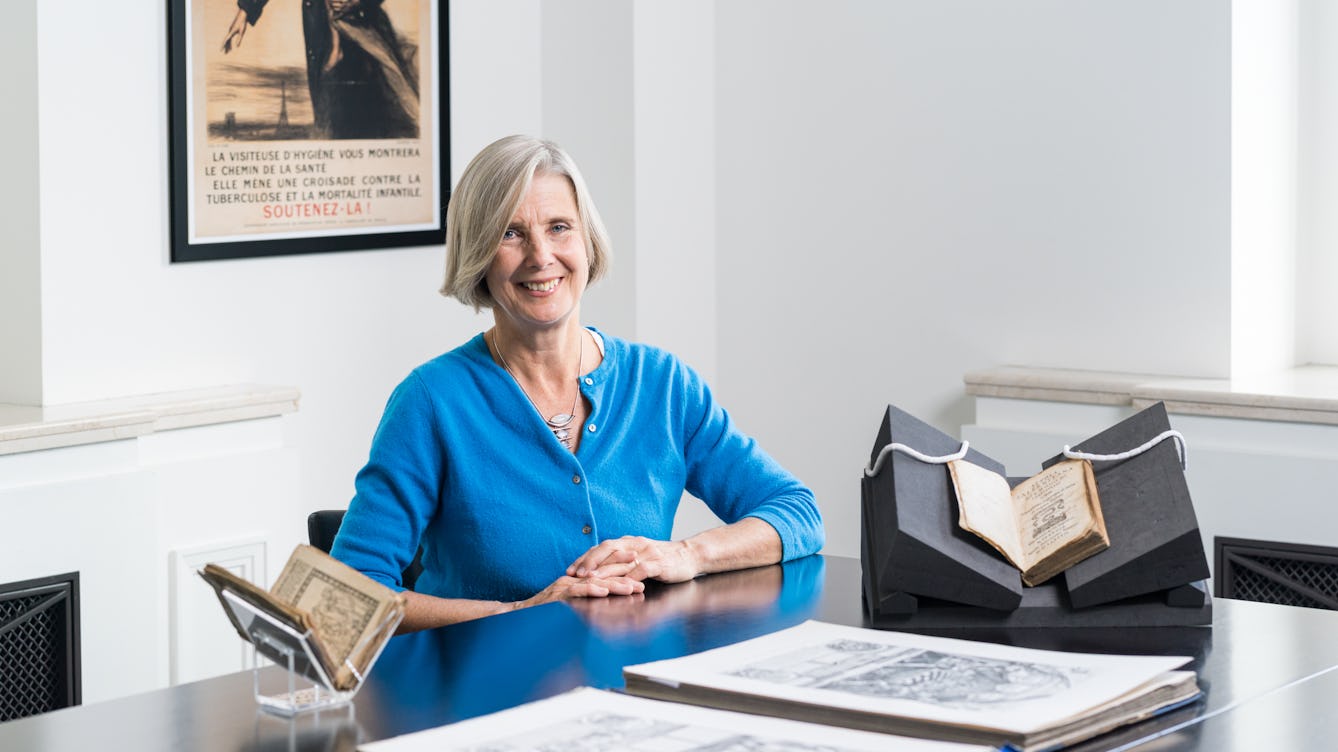 Tessa Storey with books and manuscripts in front of her on a table.