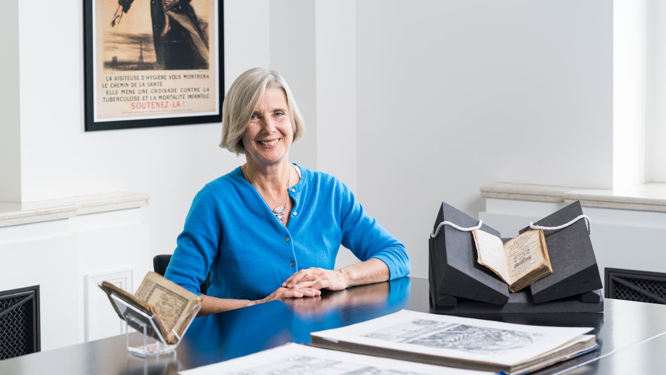 Tessa Storey with books and manuscripts in front of her on a table.