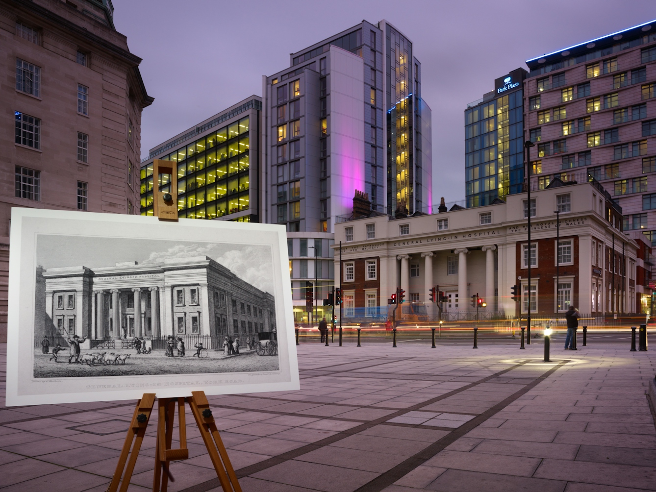 Photograph of the former General Lying-In Hospital with an historical image of the hospital displayed in front of it on a wooden artist's easel.