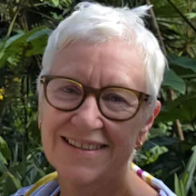 Headshot of Helen Idle with short grey hair, smiling at the camera