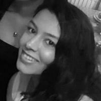 Black and white photograph of a young woman's face looking sideways at the viewer and smiling.