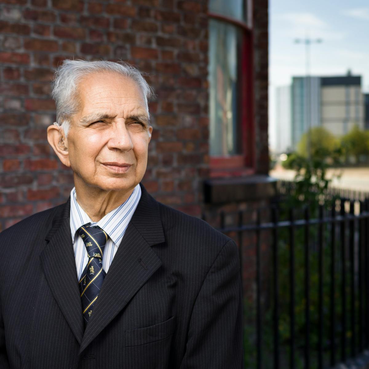 Photographic portrait of Dr Shiv Pande outside his former GP surgery. 