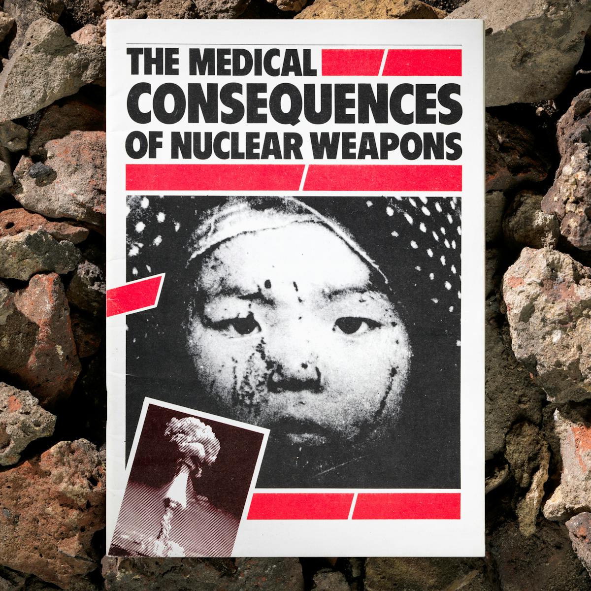 Photograph of a booklet titled, The Medical Consequences of Nuclear War, against a background of building rubble.