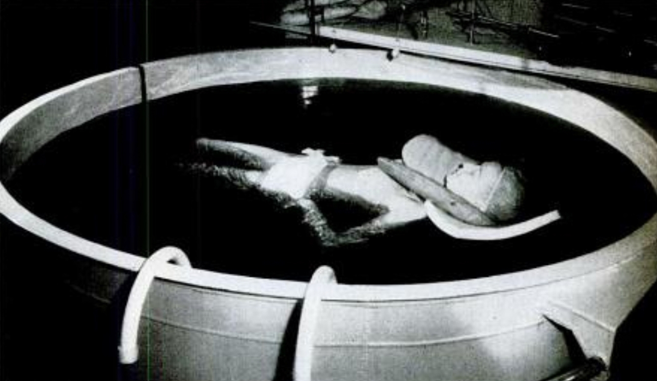 A woman floats in a tank of water on her back.