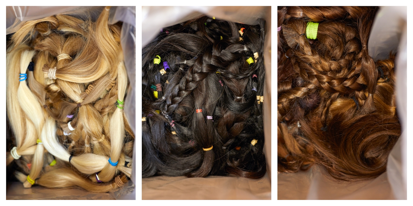 Photographic triptych. Each image is similar and shows a plastic lined cardboard box containing many hair donations, some plaited, some in a pony tail. In each image the open box is photographed from above and fills the frame. In the image on the right the box contains blonde hair, the box in the middle contains dark brown hair and the box on the right contains ginger hair.