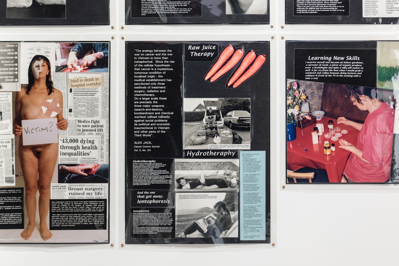 Photograph of a section of a gallery wall, showing several laminated sheets of black paper, overlaid with collages of text and imagery. 