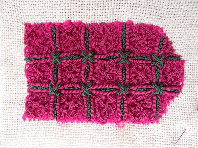 Photograph of a vibrant pink and green embroidery sample, the final sample of the almanac binding embroidery replica. 