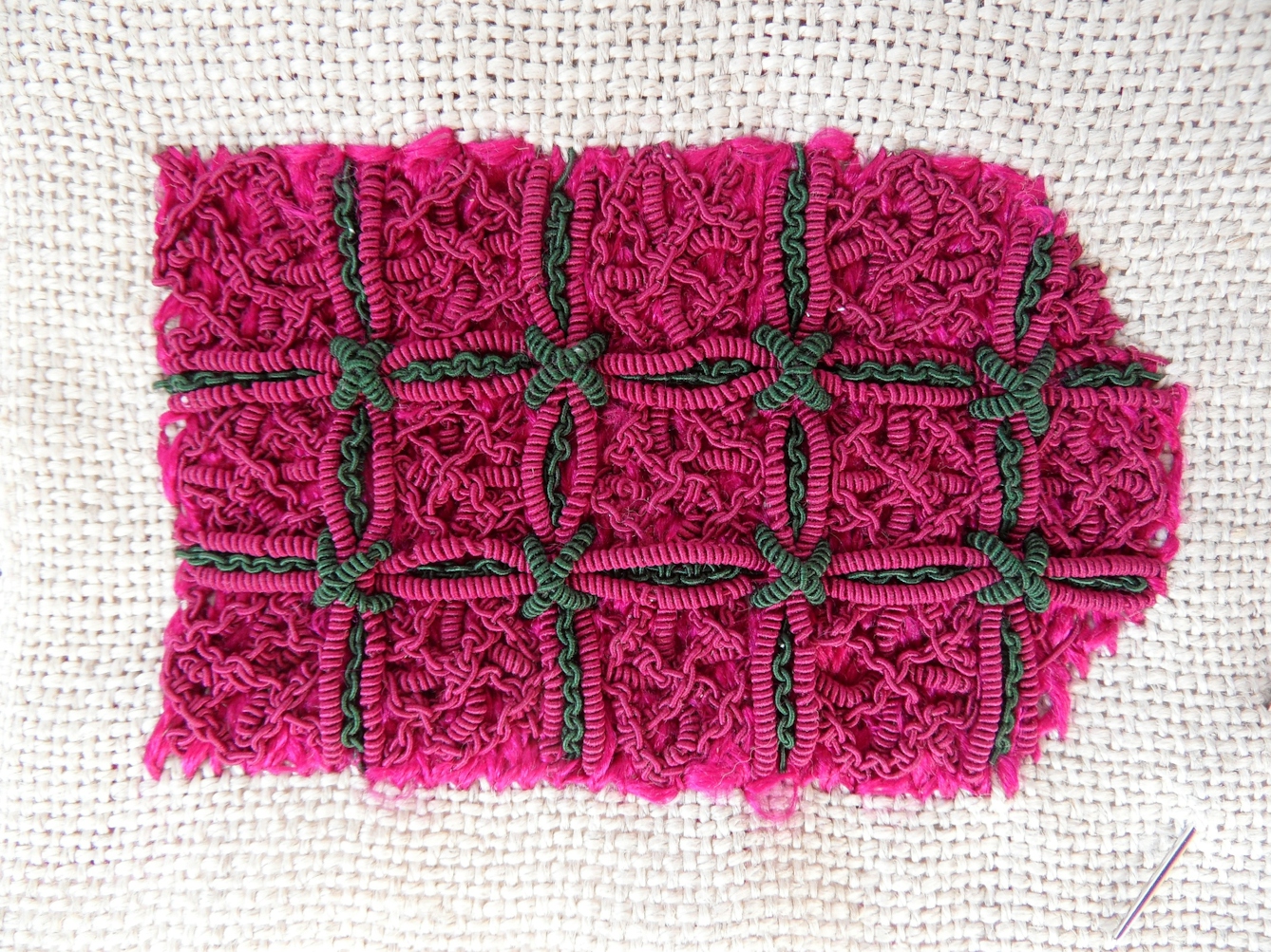 Photograph of a vibrant pink and green embroidery sample, the final sample of the almanac binding embroidery replica. 