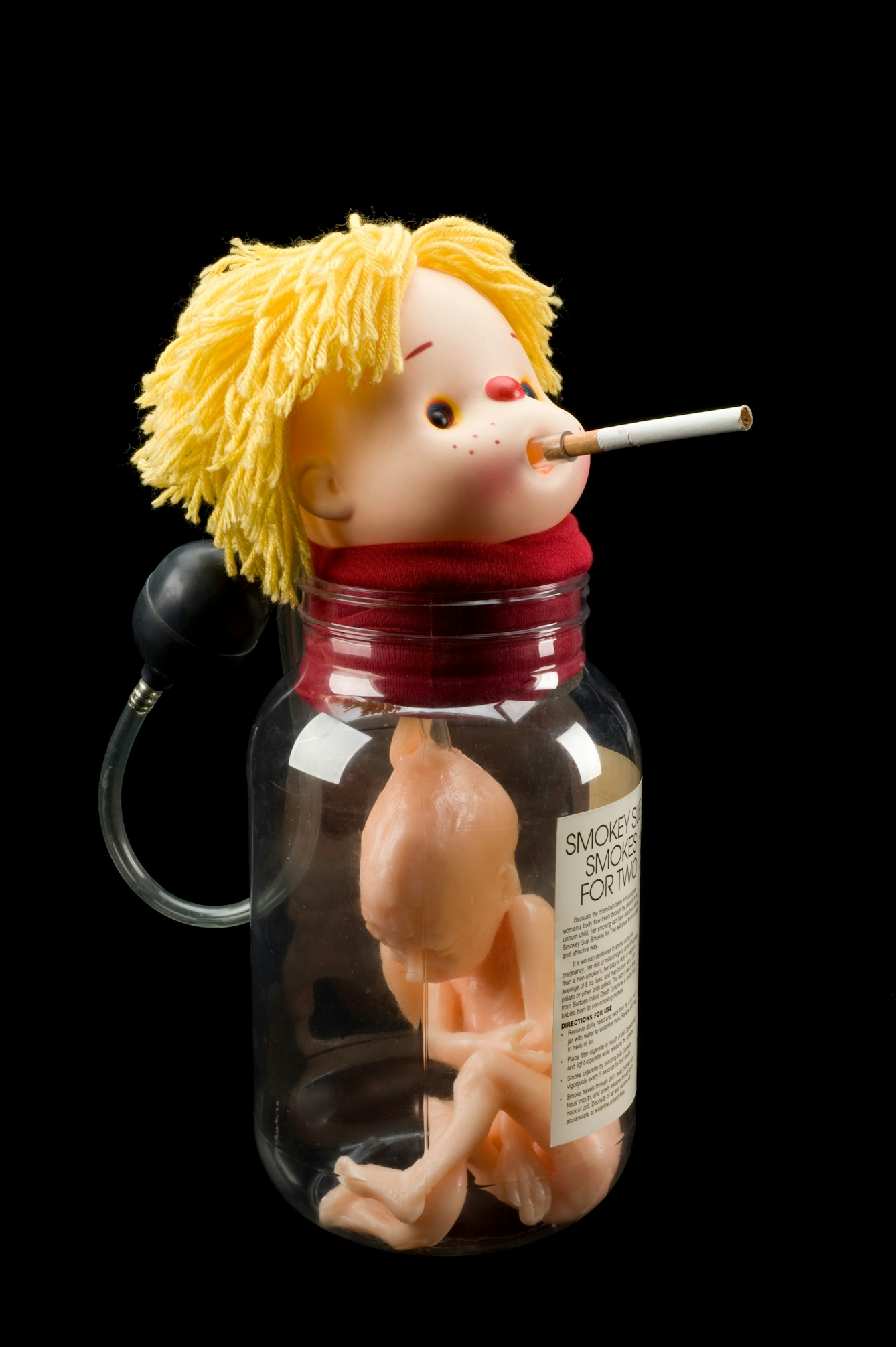 Photograph of a "Smokey Sue" doll, which features a doll's head mounted on a jar with a foetus-model inside the jar.