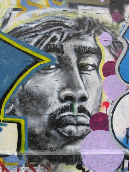 Photo of graffiti depicting the face of rapper 2Pac with colourful border