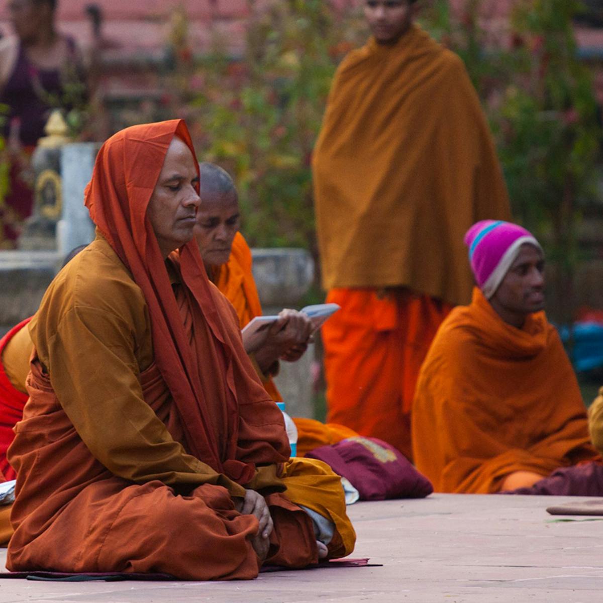 Seated people dressed in orange robes meditating.
