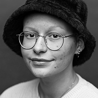 Photographic , head and shoulders portrait of Eden Magid. Eden is wearing a fury black hat.