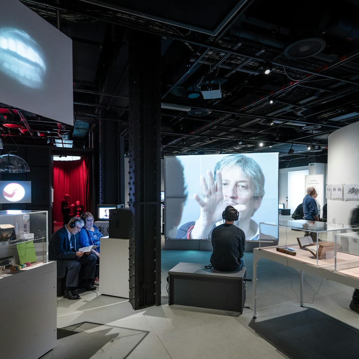 Photograph of visitors exploring the exhibition, This is a Voice at Wellcome Collection.