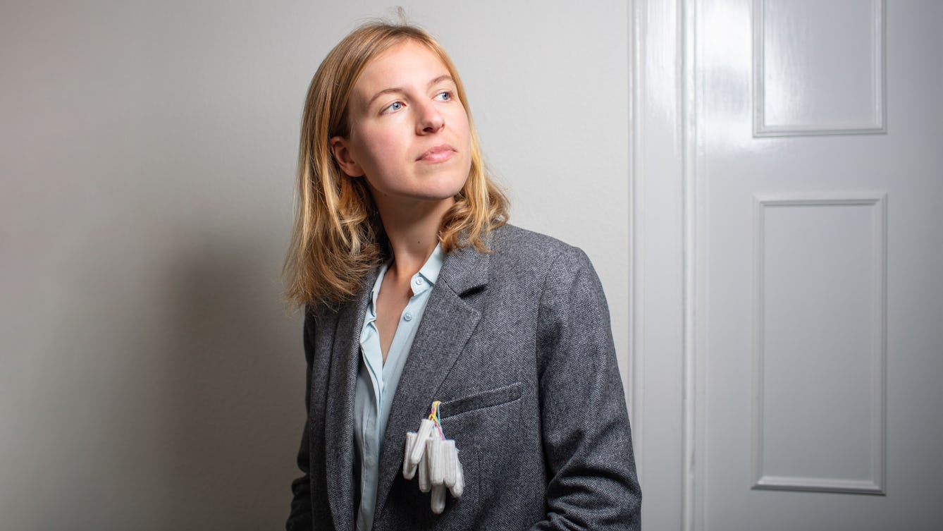 Portrait of Dr Camilla Mørk Røstvikis with tampons hanging out of the breast pocket of her blazer. 
