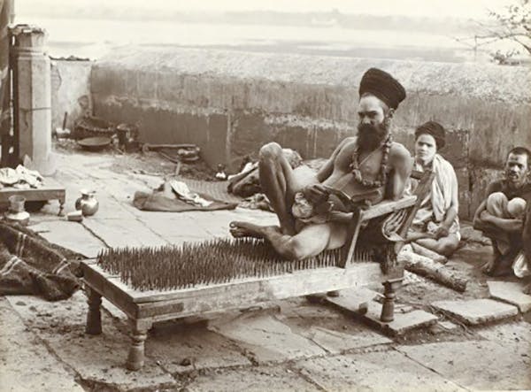 A fakir or yogi sitting on a bed fo nails