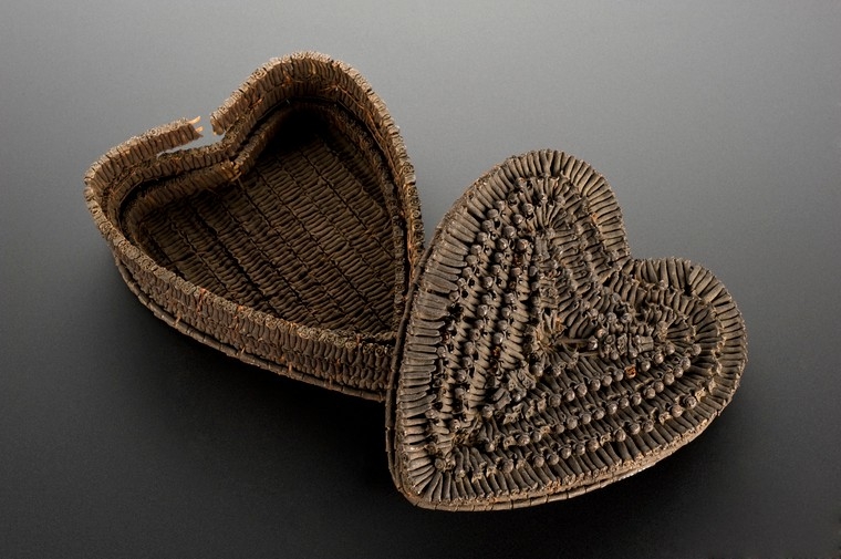 Photograph of heart shaped clove basket on grey background. The lid of the container is off in the foreground at a slight angle.