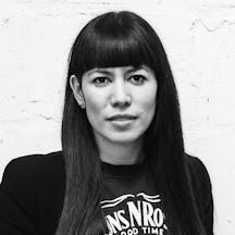 Head and shoulders photograph of a young woman with straight long dark hair wearing a heavy metal t-shirt.