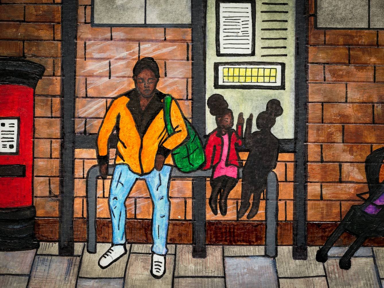 Detail from larger artwork made with paint and ink on textured watercolour paper. The artwork shows a street scene with a red post box, an industrial looking brick building and a bus stop. Sat at the bus stop is an adult in an orange top an blue trousers. Next to them is a young child in a red and pink outfit, sitting on the bench. Sitting next to them is a mirror image of them, but with the appearance of a shadow.