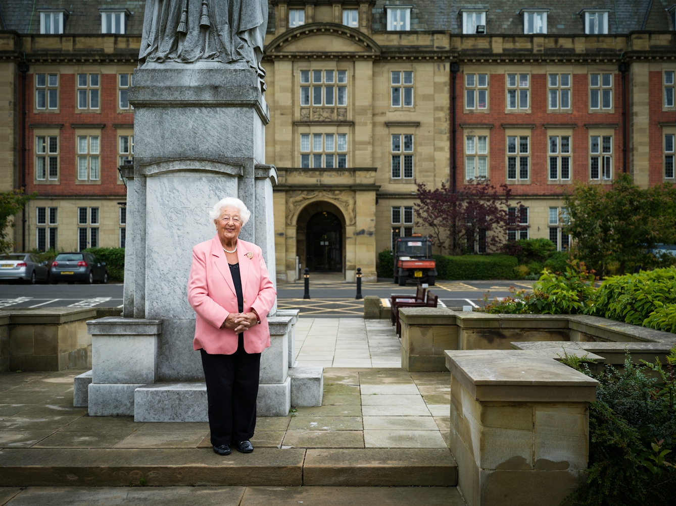 Photographic full length portrait of Ethel Armstrong, retired radiographer, outside the Royal Victoria Hospital, Newcastle upon Tyne.