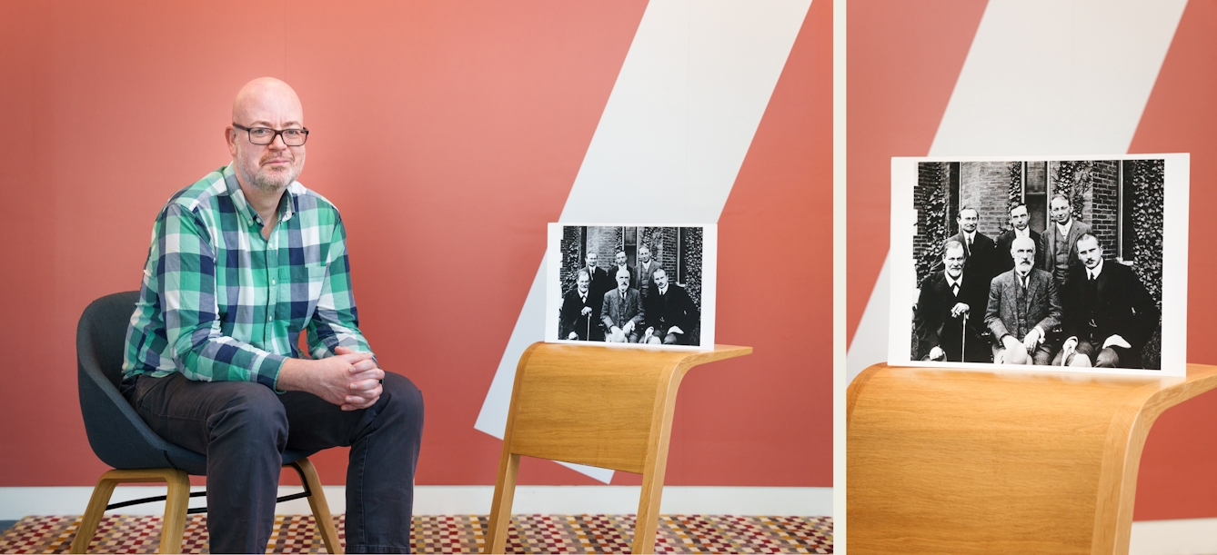 Photographic diptych made up of a landscape oriented image on the left and a portrait orientated image on the right. The left hand image shows a portrait of a man in a checked green and blue shirt sitting in a chair looking to camera. Next to him on a table is a propped up print of an archive photograph showing a group of 6 older men posing for the photograph. The three men on the front row all have facial hair of some description. The image on the right is a closeup detail of the archive image.