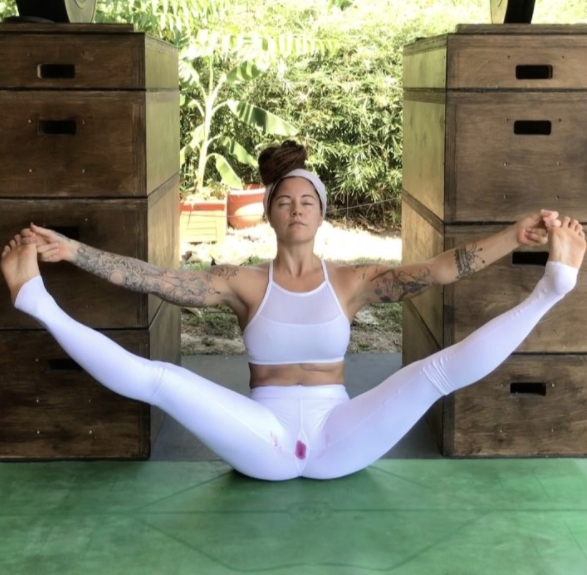 Steph Gongora sitting in yoga pose wearing white leggings stained with blood