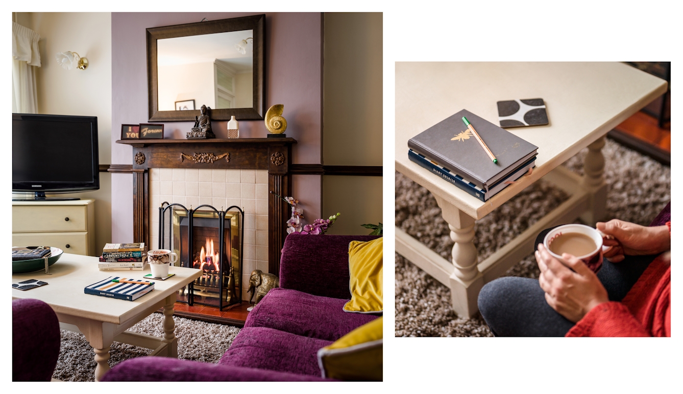 Photographic diptych showing a living room with a fire burning in the fireplace, a sofa, tv and coffee table, on the left and a close-up of hands holding a hot drink with a pen and note pads on a coffee table, on the right.