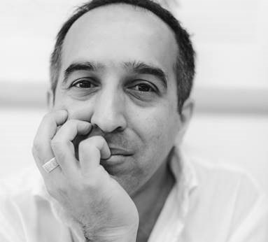 A headshot black and white photograph of a man resting his chin in his hand