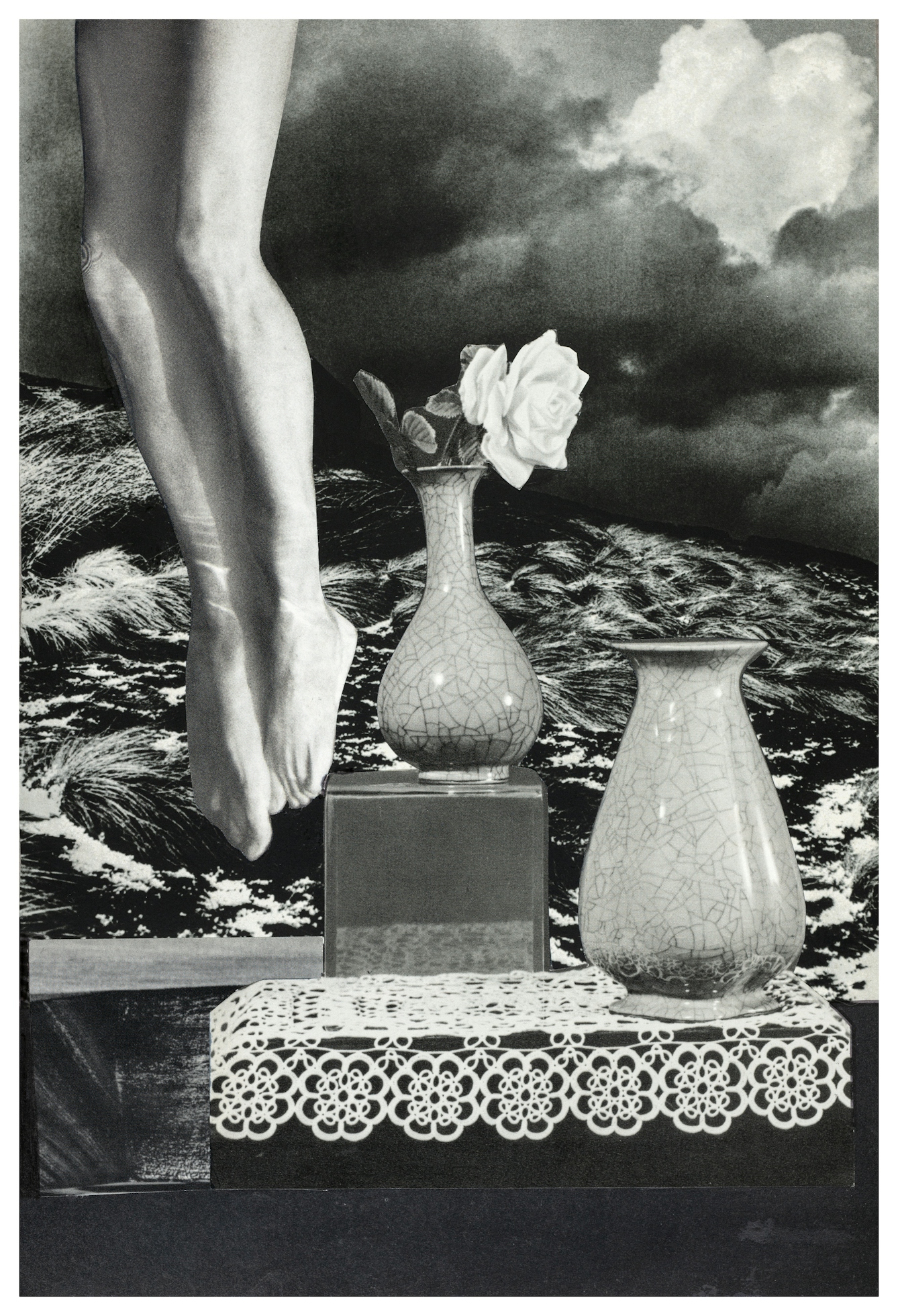 Photographic collage using images cut out from magazines and books. The scene depicts a pair of naked legs from the thigh down to the toes appearing from the top left hand corner. Next to the legs are 2 vases resting on a square plinth and a crocheted table cloth. One vase has a white rose in it, the other is empty. The background of the scene is a wind swept sand dune landscape against a heavy cloudy skyline. The overall tones of the collage are monotone, blacks, whites and greys.