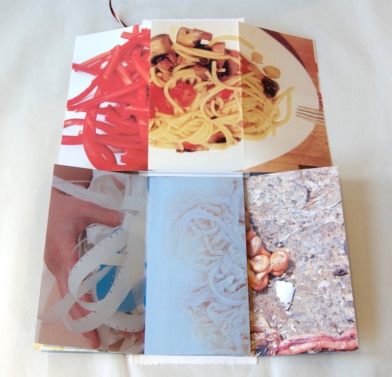 The infolded interior of the artist's book ‘Huwawa in the Everyday’ showing four photographs of entangled spaghetti, sausage skins, paper strips and entrails.
