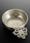 Photo of silver coloured round dish with ornate handle.