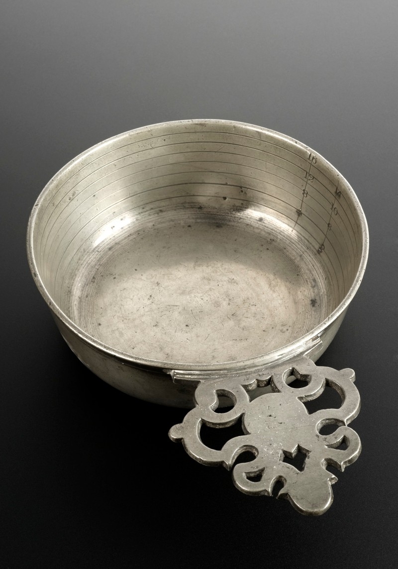 Photo of silver coloured round dish with ornate handle.