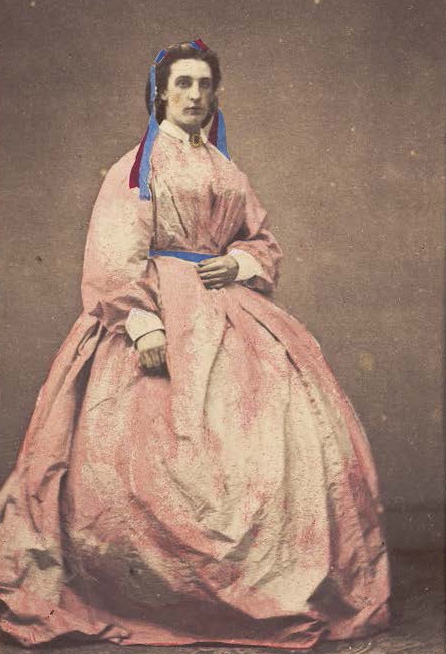 A man in drag poses wearing a large pink dress, photograph, c.1890