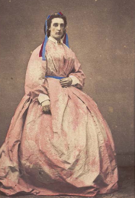 A man in drag poses wearing a large pink dress, photograph, c.1890