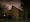 Photograph of Woodford spiritualist church, London at night. The architecture of the church is such that it the apex of the pitched roof is off centre to the left. The construction is bare brick with stairs to the entrance on the right.