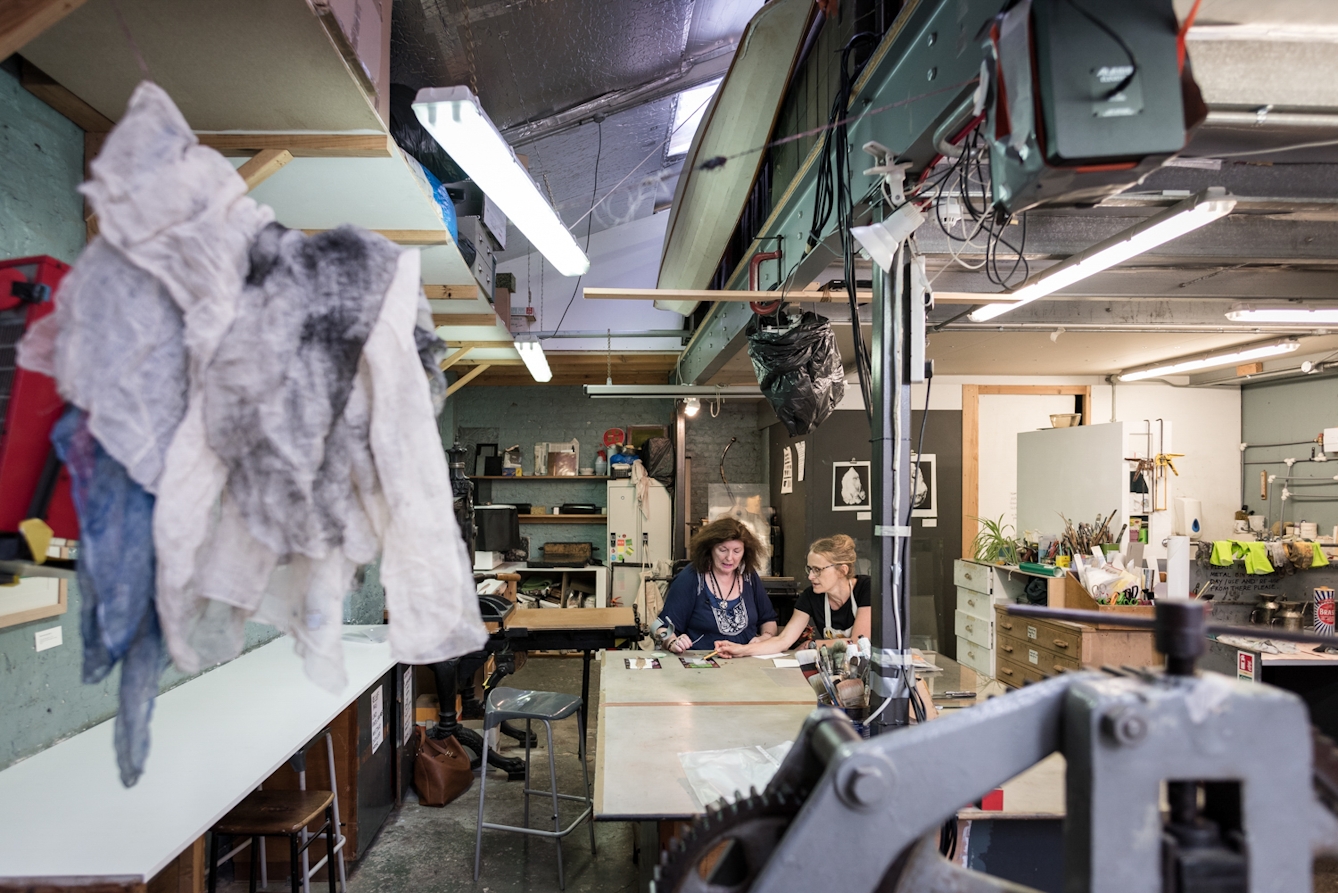 Photograph of two women talking in a printmaking studio.