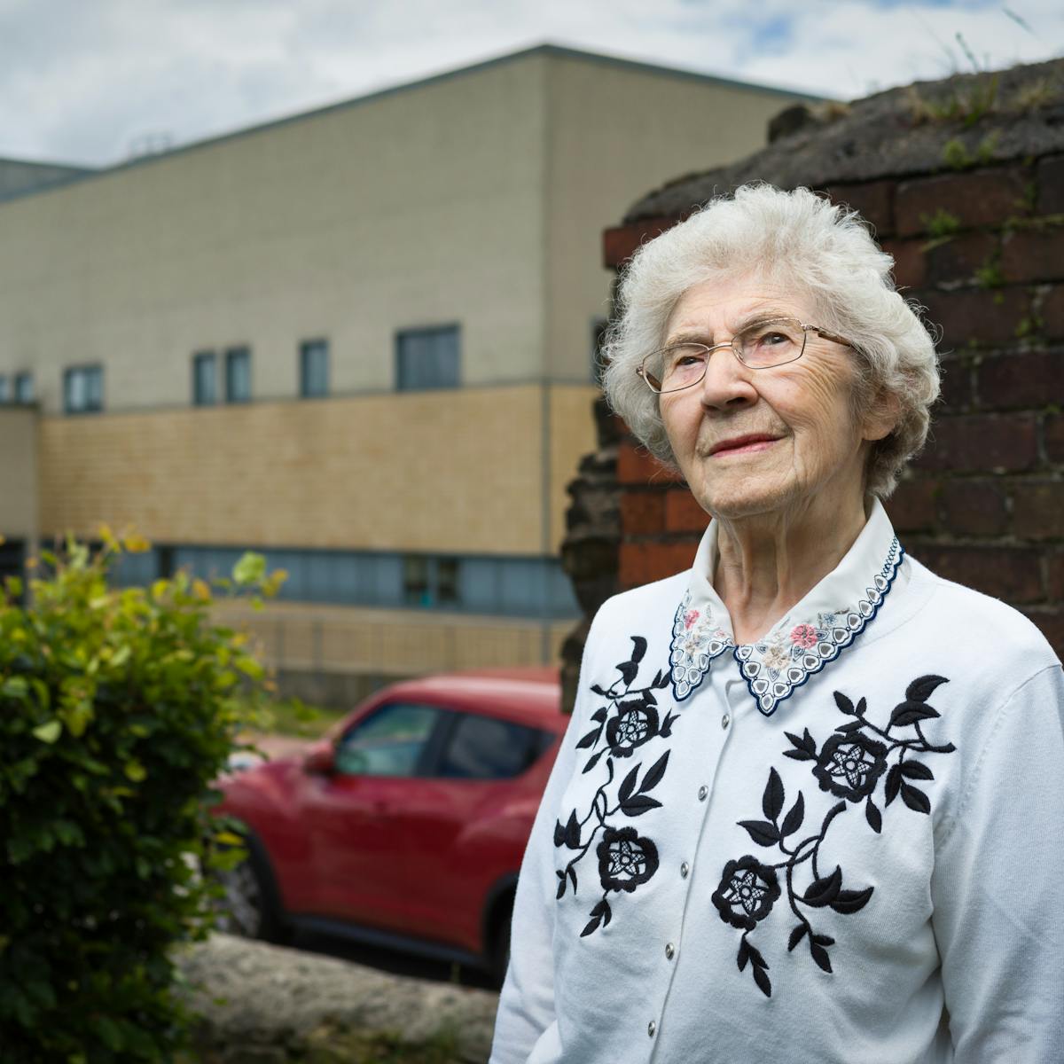 Photographic portrait of Joyce Thompson standing in front of the Royal Blackburn Hospital.