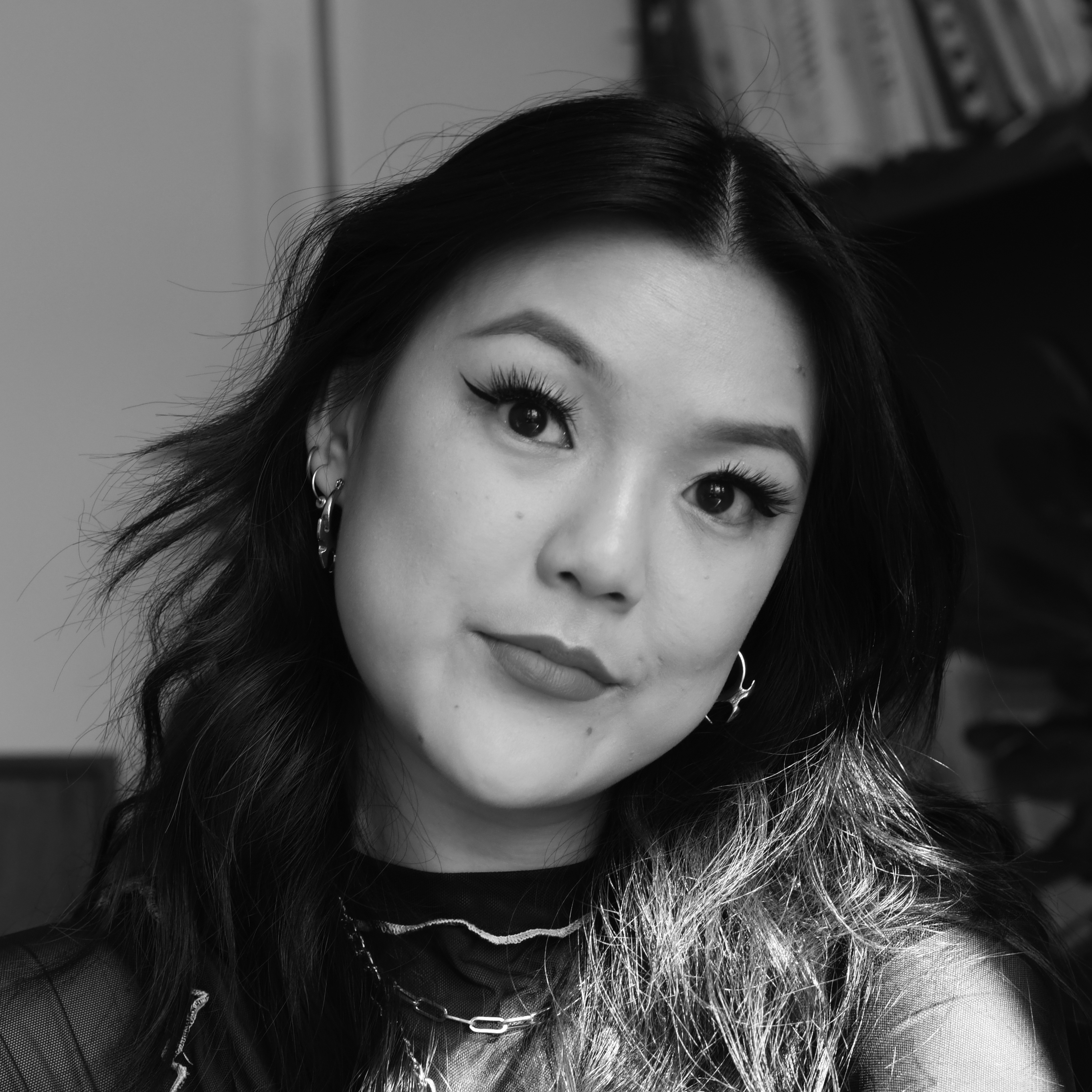 Head and shoulders photograph of a young woman with her head tilted to the right, wearing earrings, with dark, shoulder-length hair.
