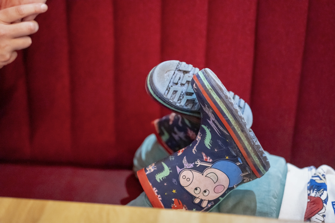 A photograph of a child laying on seat, with their colourful wellington boots sticking up in the air.