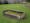 Photograph of a grave in St James's Gardens. The stone from the top of the grave has been dislodged exposing the earth beneath it.