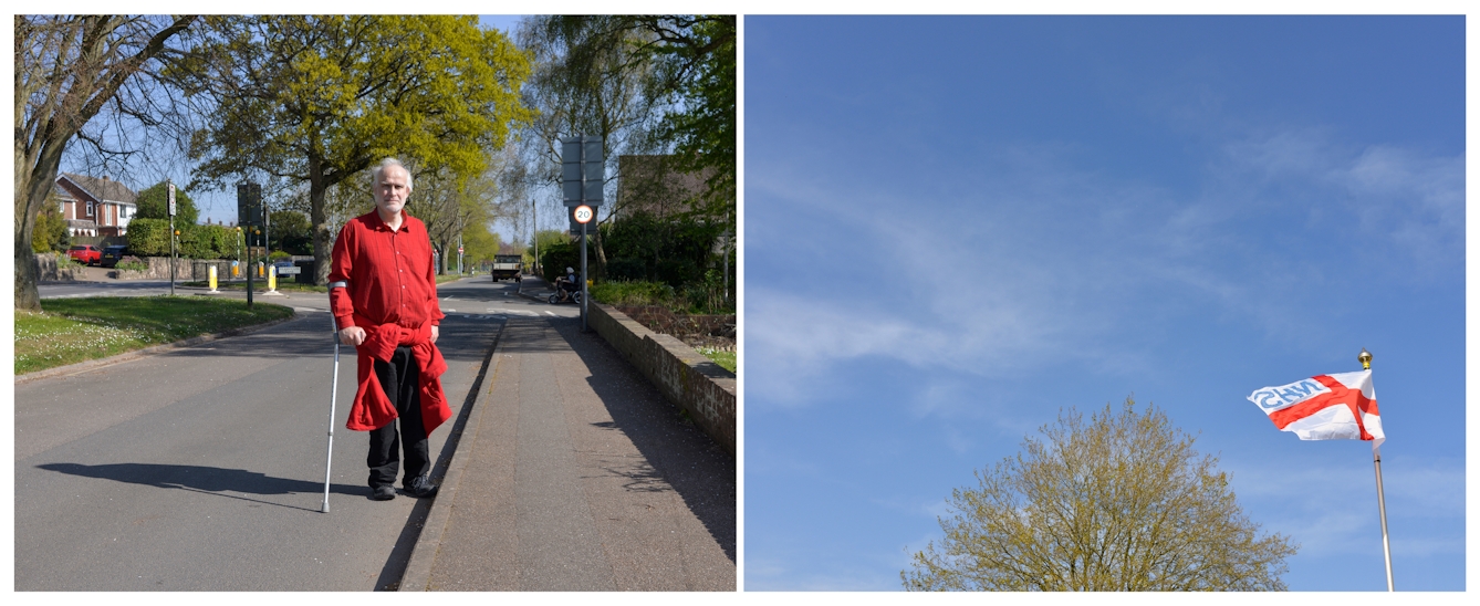 A photographic diptych. The image on the left shows a middle-aged man with grey hair wearing a red shirt and black trousers holding a crutch in his right hand. He stands in the 20 MPH zone road which has a small central reservation lined with trees.  The image on the right shows a blue sky on the bottom right of which is the St George’s flag flying with NHS (from the reverse side) written in blue in the top left quarter. To the left of the flag, is the top of a large tree lightly covered in yellow green foliage. 
