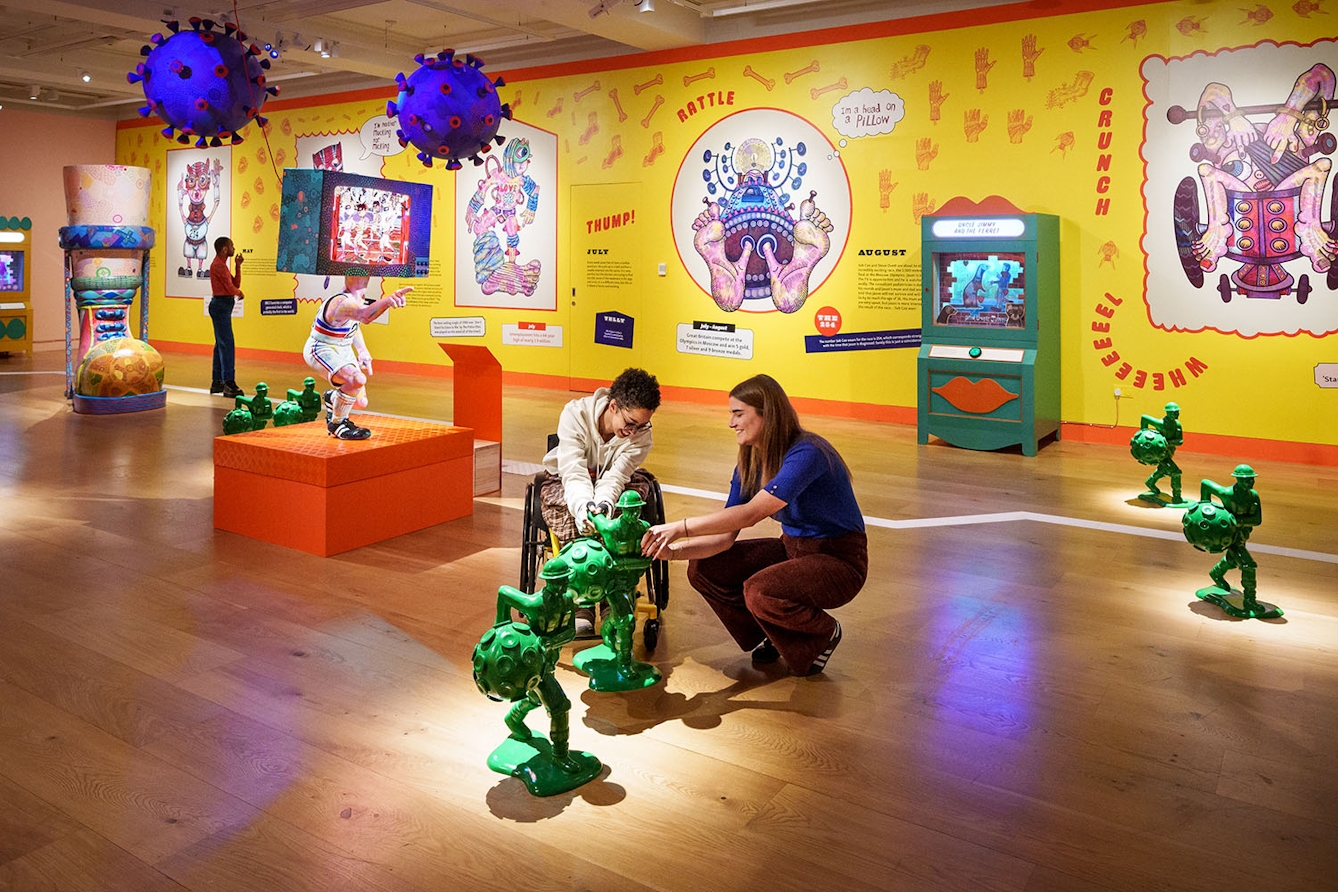 Photograph of two people touching a group of sculptures in the exhibition. 